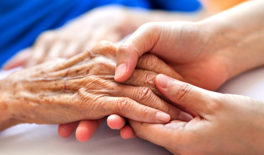 Caregiver holding elderly patient's hand